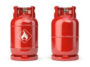 Two red gas cylinders are shown side by side. The cylinder on the left features a white warning label with a flame symbol, indicating flammable and combustible liquids. Both cylinders have a metal valve on top and are identical in shape and size.