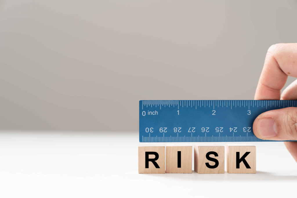 A hand holding a blue ruler measures wooden blocks that spell "RISK," representing the importance of precise planning in Emergency Action Plans (EAP).