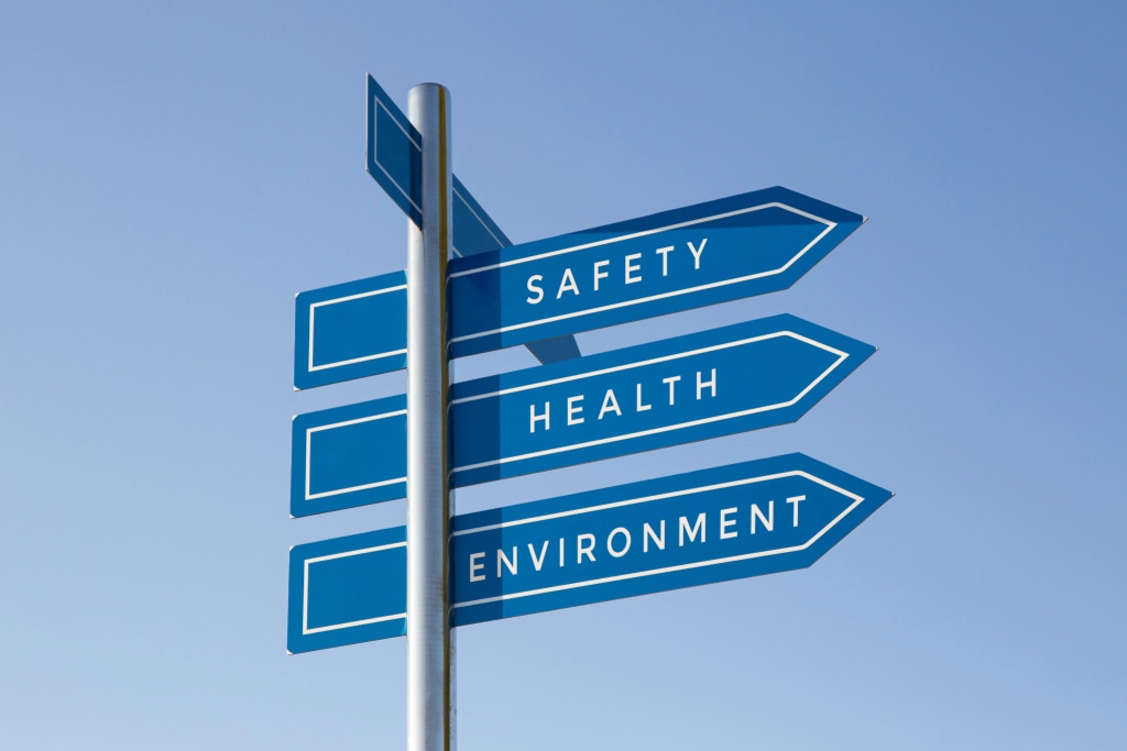 A blue signpost with three arrowed signs pointing right, labeled "Safety," "Health," and "Environment" against a clear blue sky.